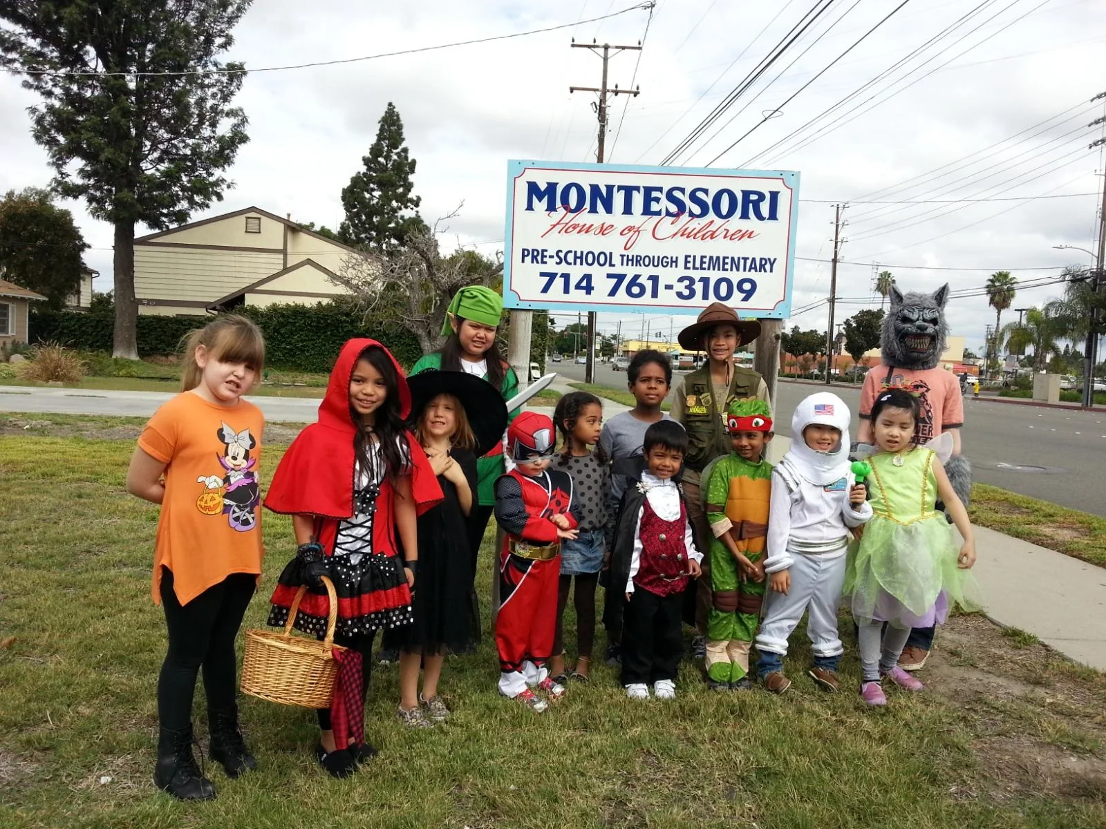 Children in costumes by the Montessori House of Children sign